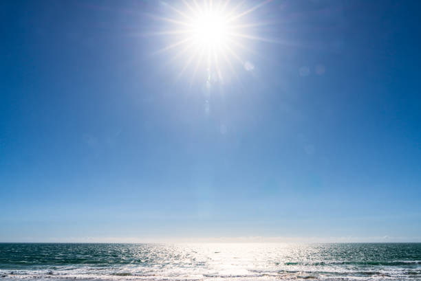 The summer sun in the sky, reflecting on the surface of the sea below