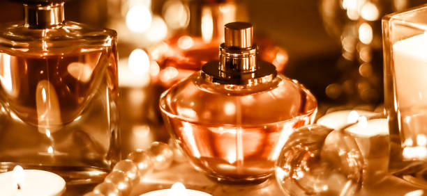 Close-Up Of Perfume Sprayer Bottles By Illuminated Tea Light Candles On Table