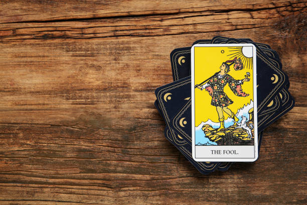 The Fool and other tarot cards on wooden table, flat lay