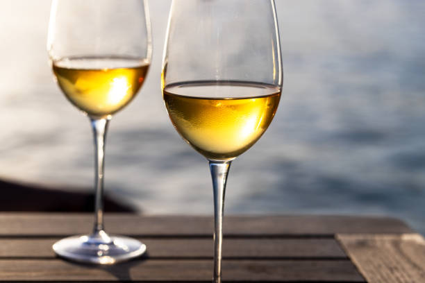 Two glasses with white wine on the table , sea water in background